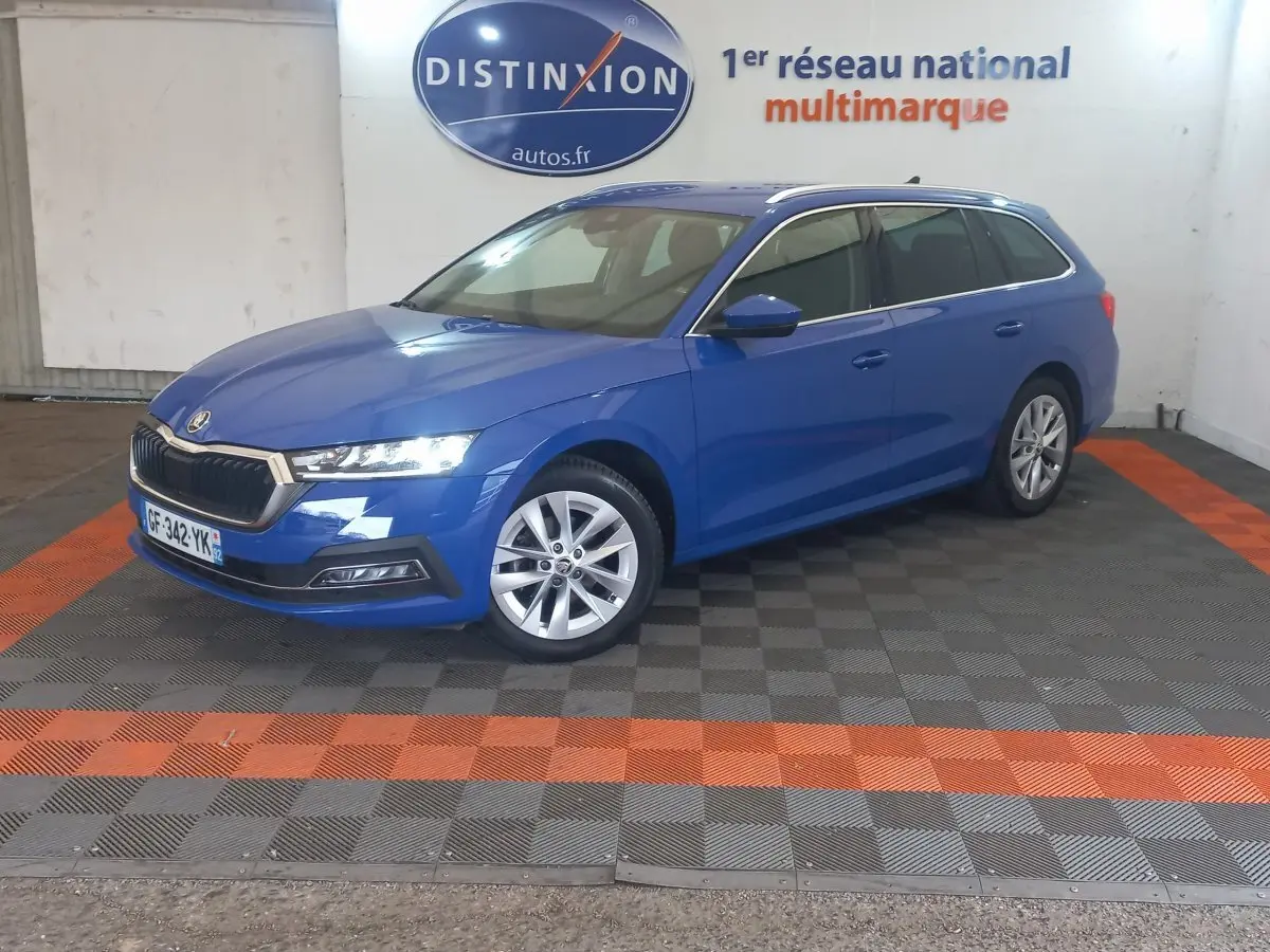 Vue 3/4 avant droite d'une Skoda Octavia break bleu 2022, avec jantes alliage et phares LED allumés.