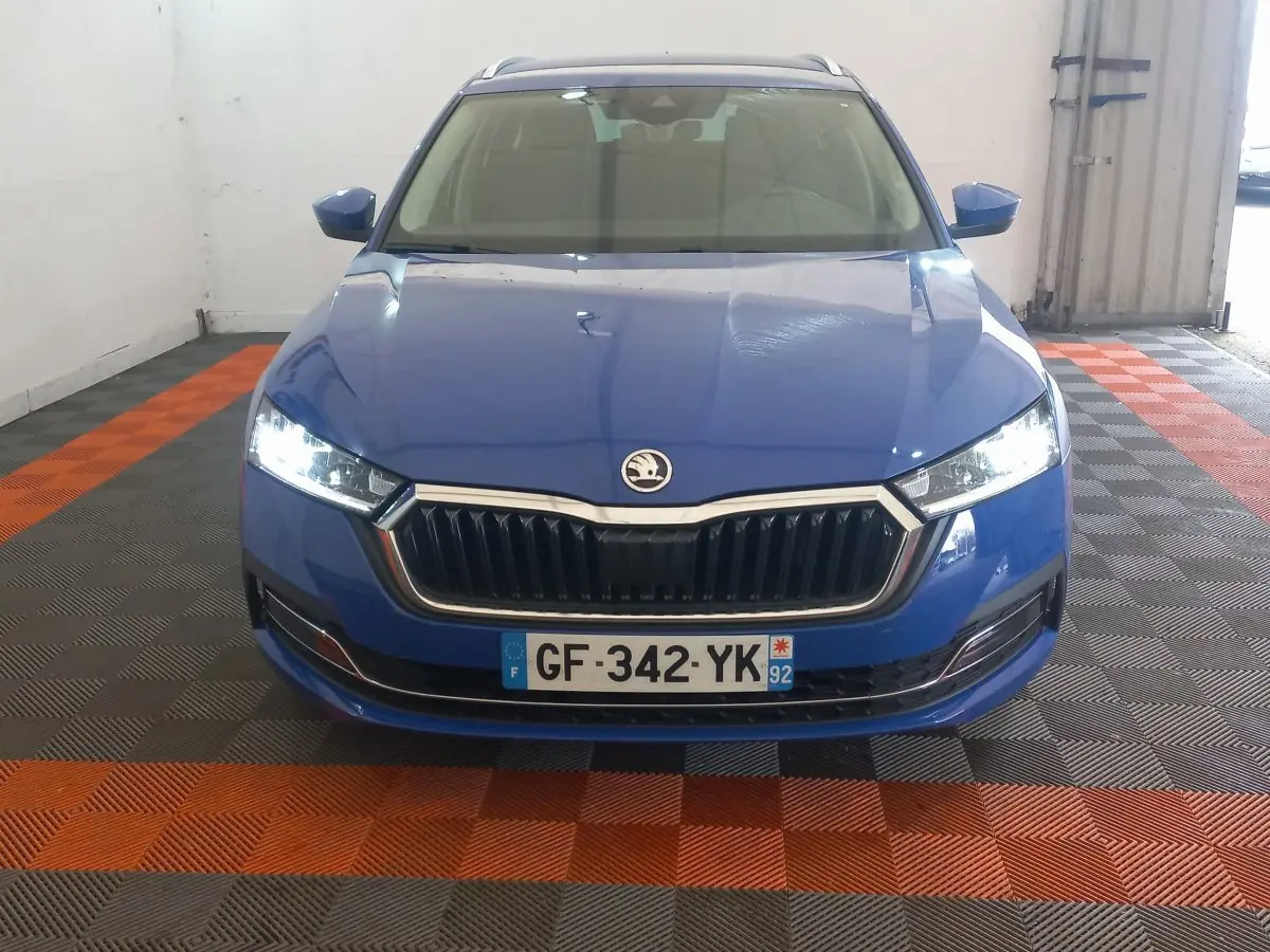 Vue frontale d'une Skoda Octavia bleu électrique avec phares LED allumés dans un garage.