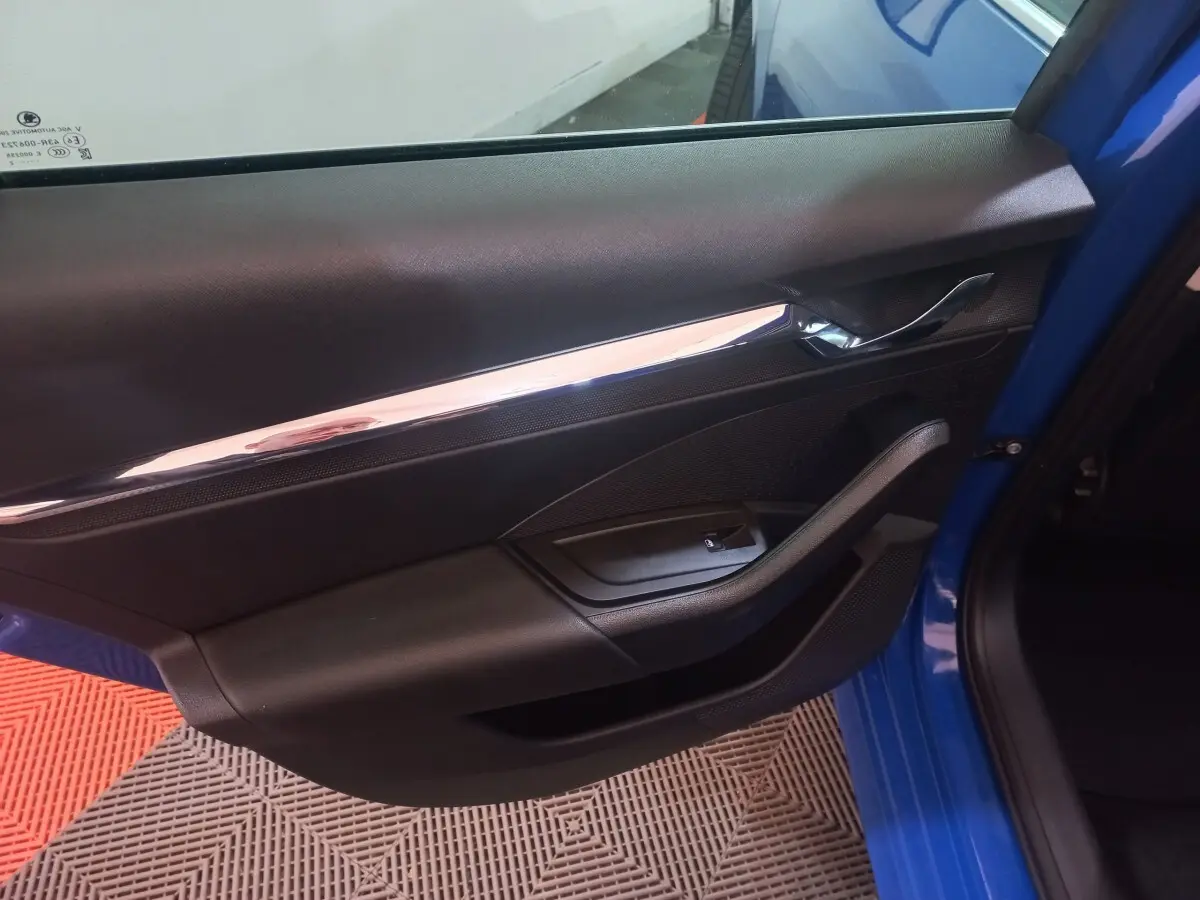 Vue rapprochée de la porte avant gauche bleue de la Skoda Octavia 2022, avec poignée chromée et commande de vitre noire.