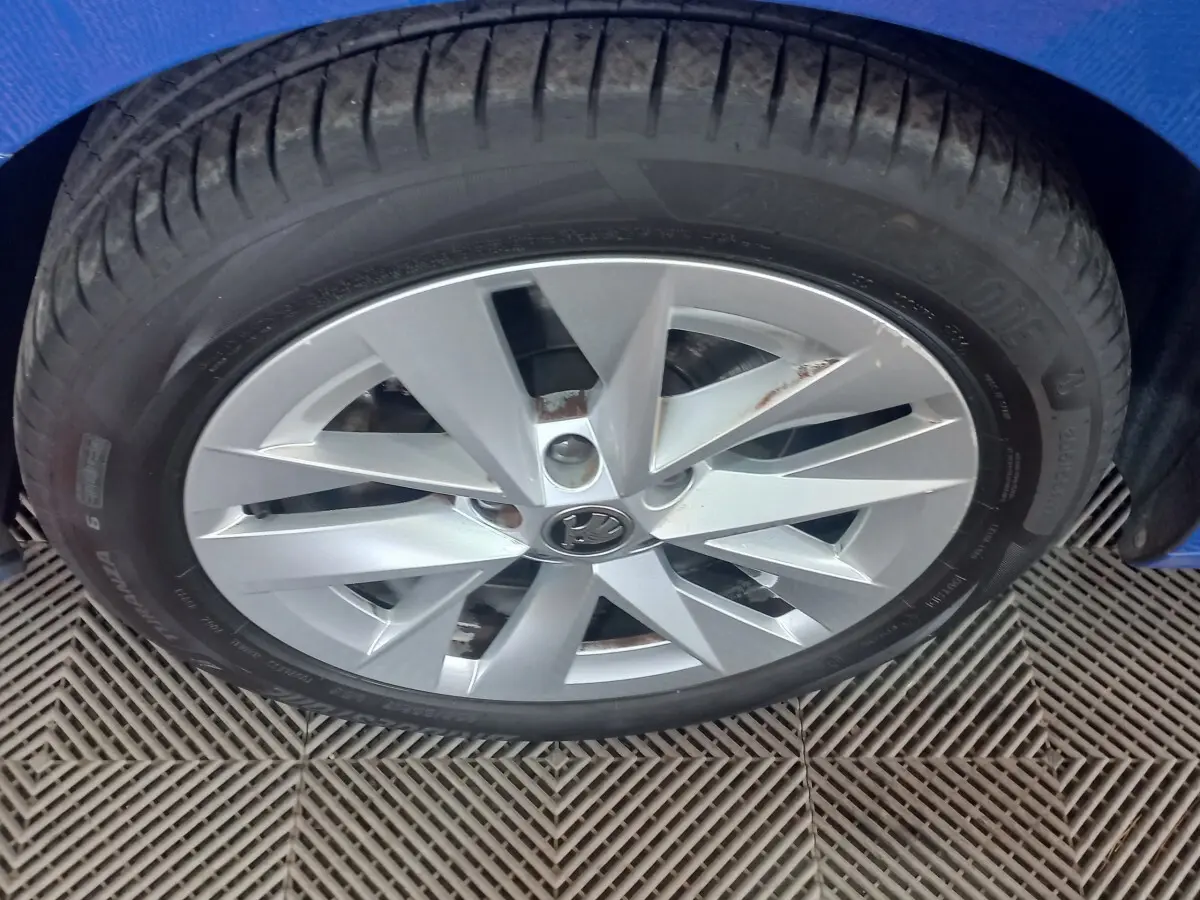 Gros plan sur la roue avant gauche d’une Skoda Octavia bleue, jante alliage argentée à 10 branches.