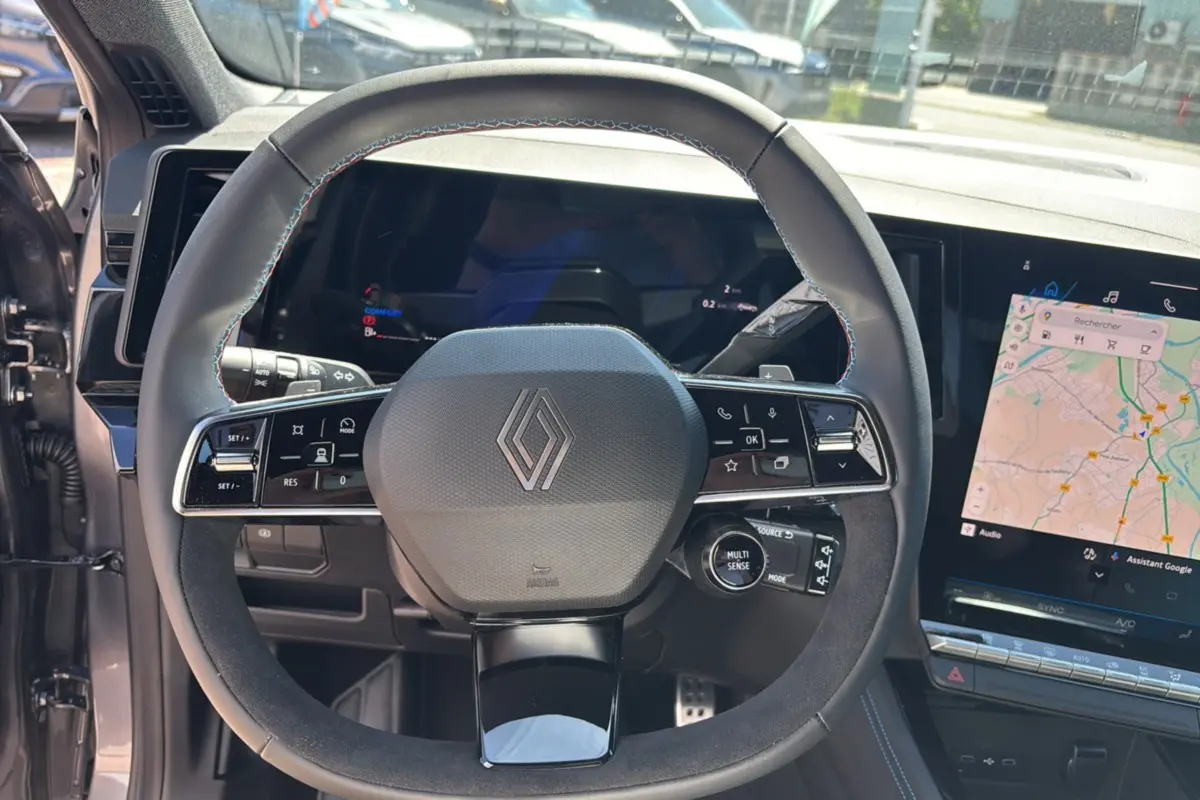 Vue rapprochée du volant cuir multifonctions avec logo Renault et écran tactile GPS sur Renault Austral E-Tech 200 Esprit Alpine.