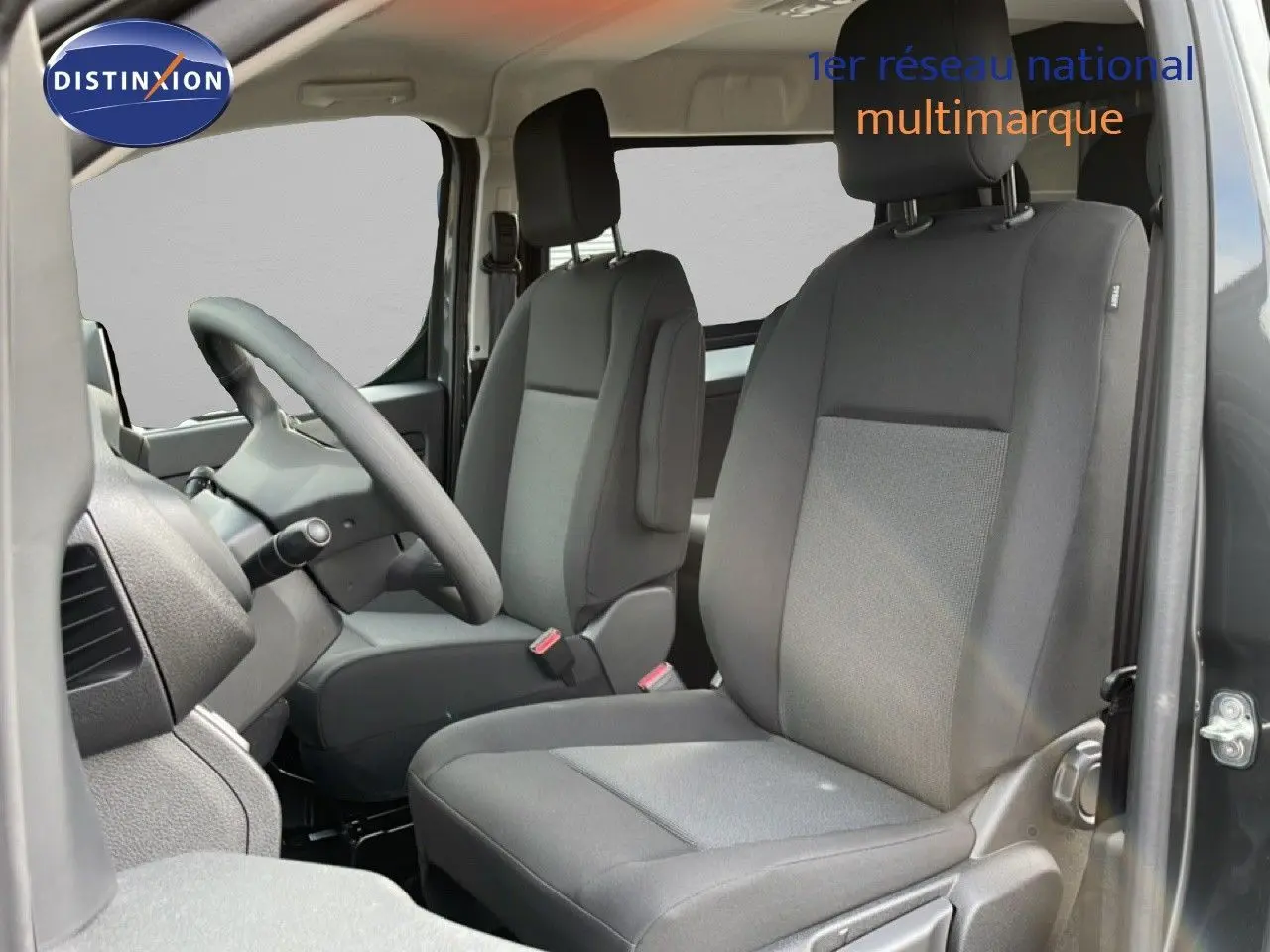 Vue intérieure côté conducteur du Citroën Jumpy Cabine Approfondie gris titane, avec sièges tissu gris et volant multifonction.