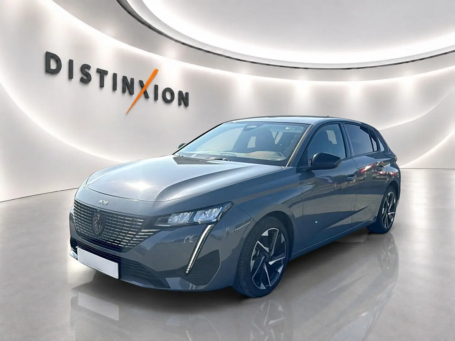 Peugeot 308 gris Artense vue 3/4 avant droit dans un showroom lumineux avec jantes alliage noires et grises.