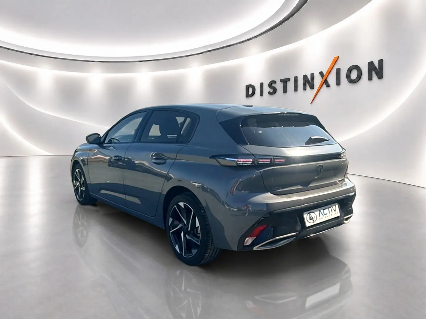 Peugeot 308 gris Artense vue 3/4 arrière droit dans un showroom lumineux avec jantes alliage noires.