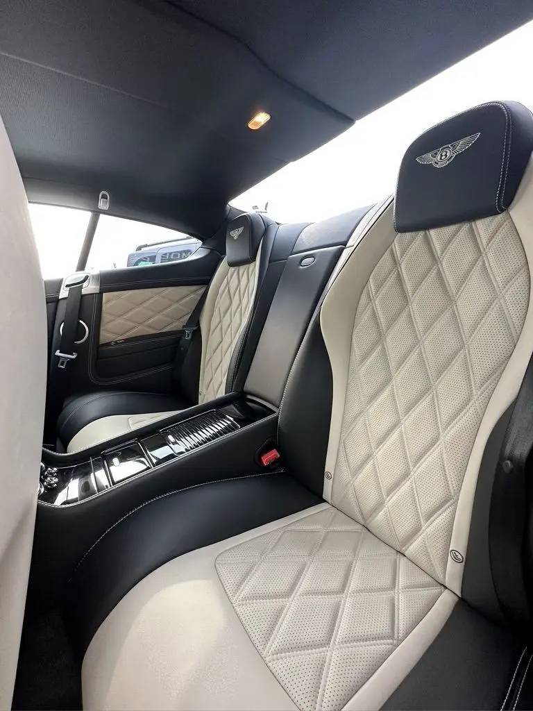 Vue intérieure arrière de la Bentley Continental GT 4.0 V8 Mulliner 2013, sièges cuir noir et beige avec surpiqûres diamantées.