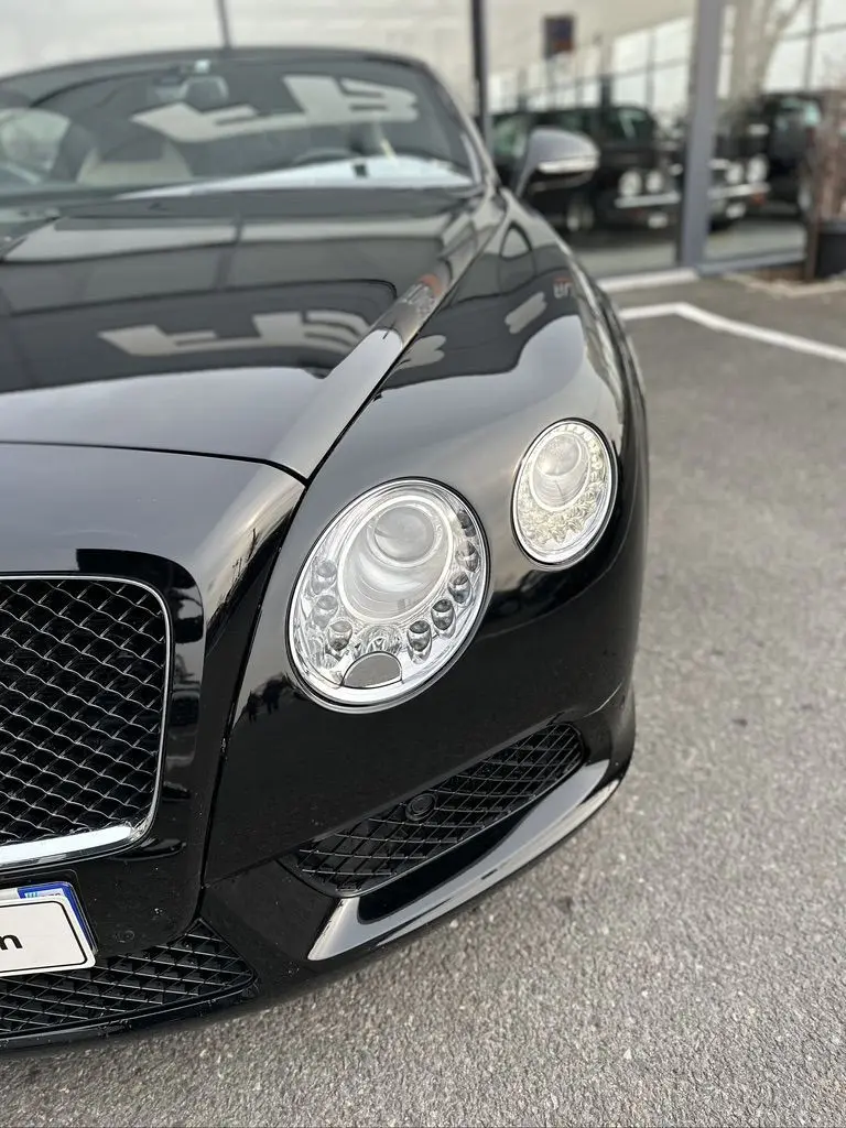 Vue rapprochée avant droite de la Bentley Continental GT Mulliner noire mettant en valeur ses phares ronds distinctifs.