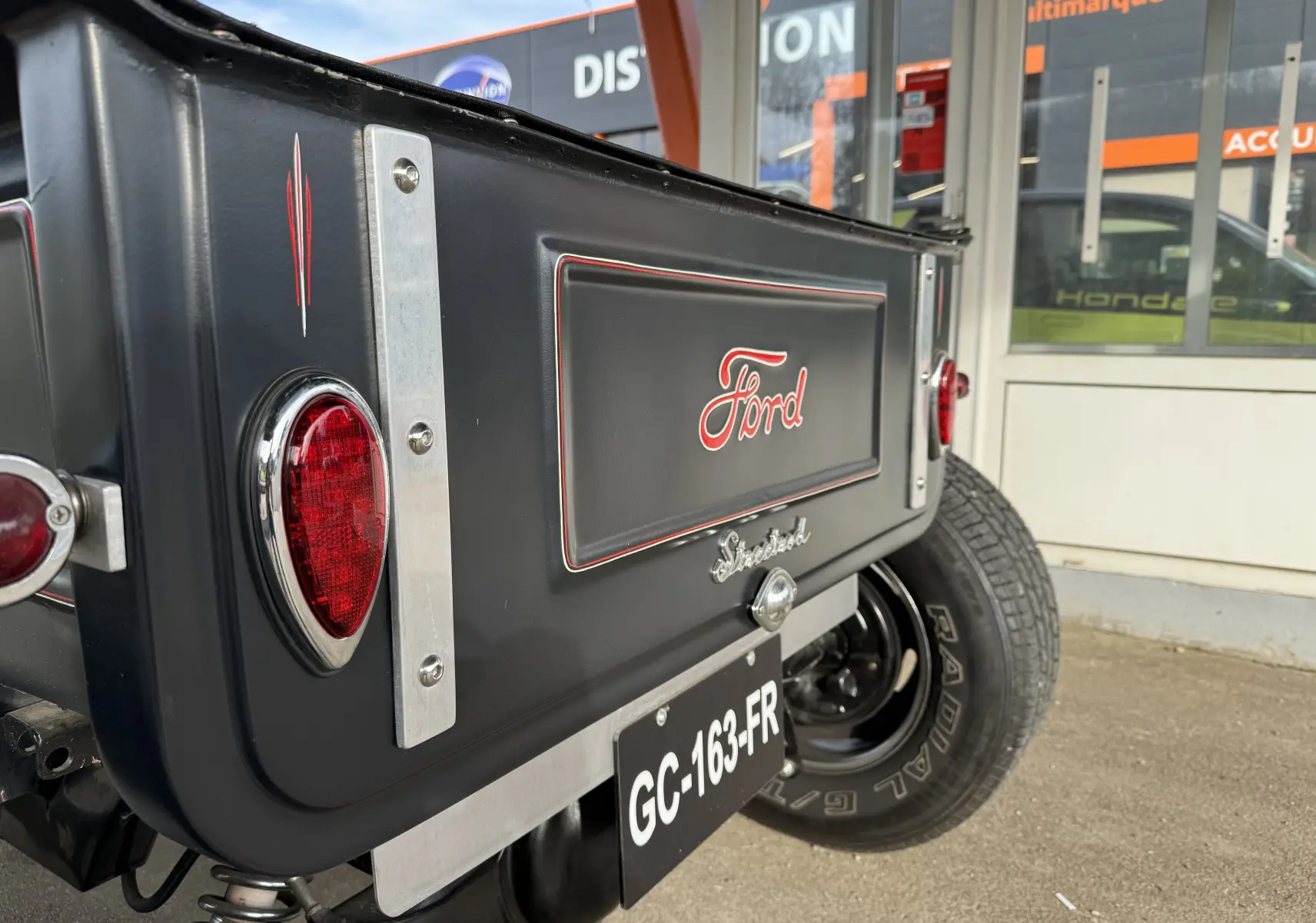 Vue arrière droite du Ford T Hot Rod noir avec feux ronds rouges et logo Ford en relief sur la malle.