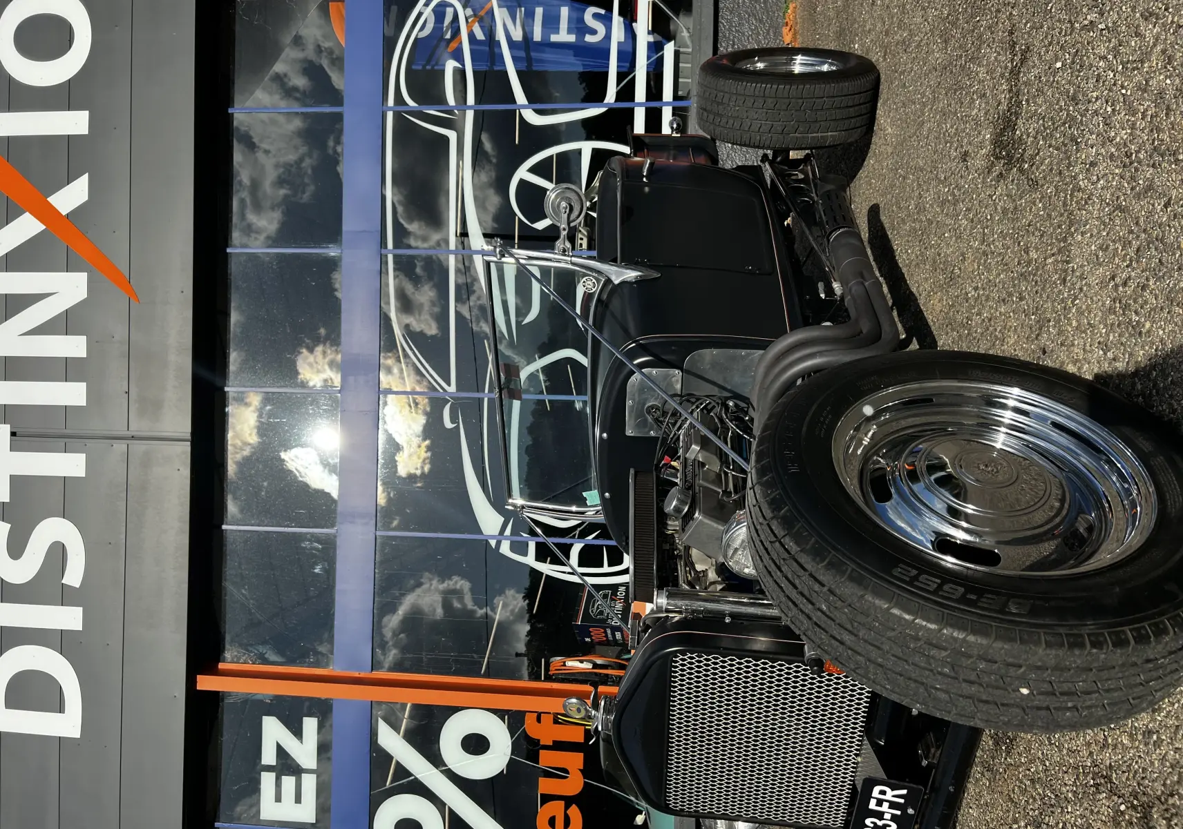 Vue de face en léger 3/4 droit d'une Ford T Hot Rod V8 noire avec moteur apparent et jantes chromées brillantes.