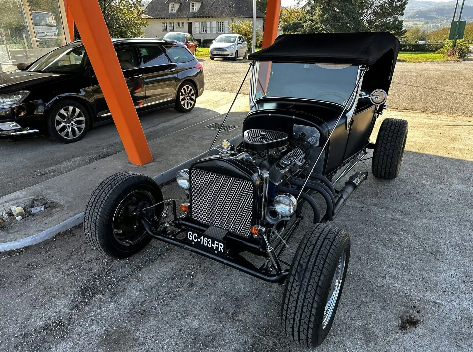 Ford T Hot Rod V8 noir vu en 3/4 avant droit, capote noire relevée et moteur V8 apparent au détail.