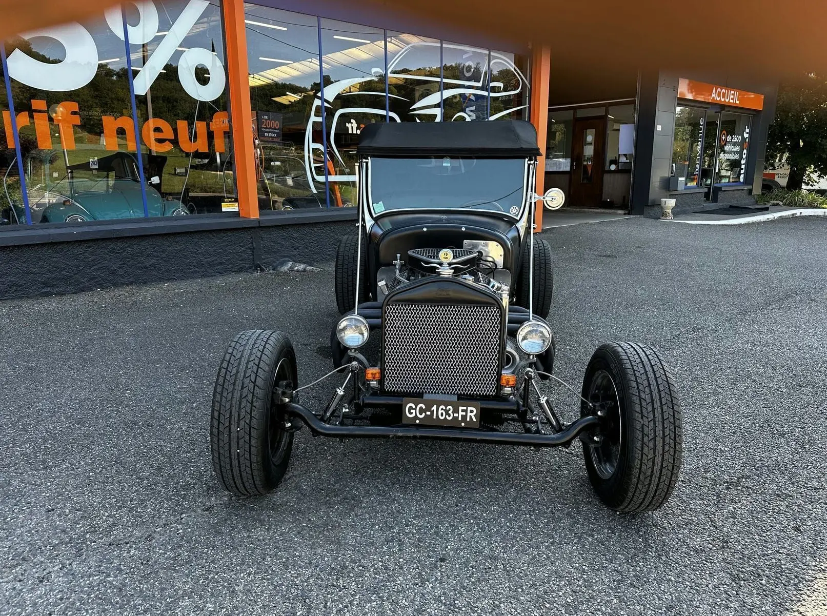 Vue frontale d'une Ford T Hot Rod V8 noire avec capote noire et calandre métallique ajourée.
