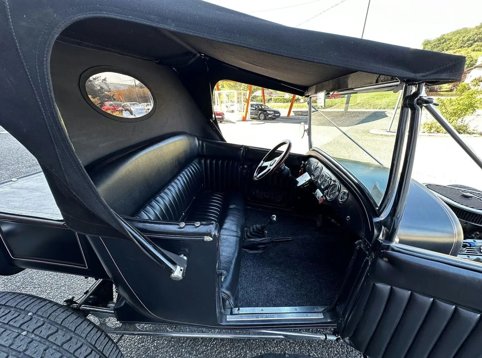 Vue latérale gauche de l'intérieur noir cuir du Ford T Hot Rod V8 1923 avec capote et tableau de bord visible.