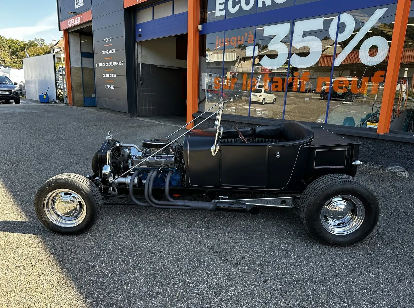 Ford T Hot Rod V8 noir vu de profil côté gauche, moteur apparent et intérieur cuir noir décapotable.