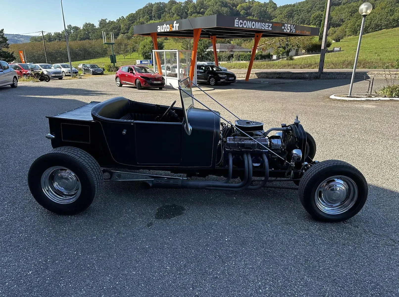 Ford T Hot Rod V8 noir vue de profil côté gauche, capot moteur ouvert et intérieur décapotable visible.