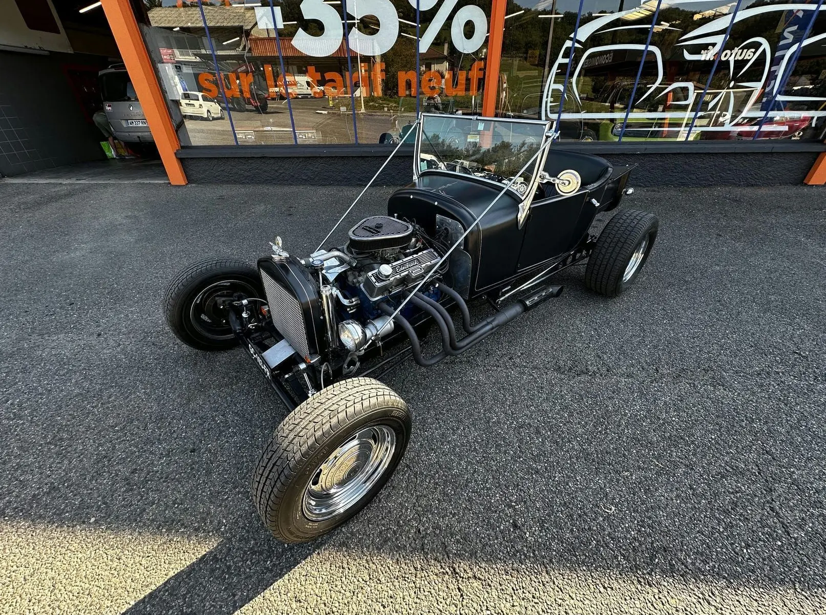 Ford T Hot Rod V8 noir vue 3/4 avant droit, capote décapotée et moteur V8 apparent avec détails chromés.