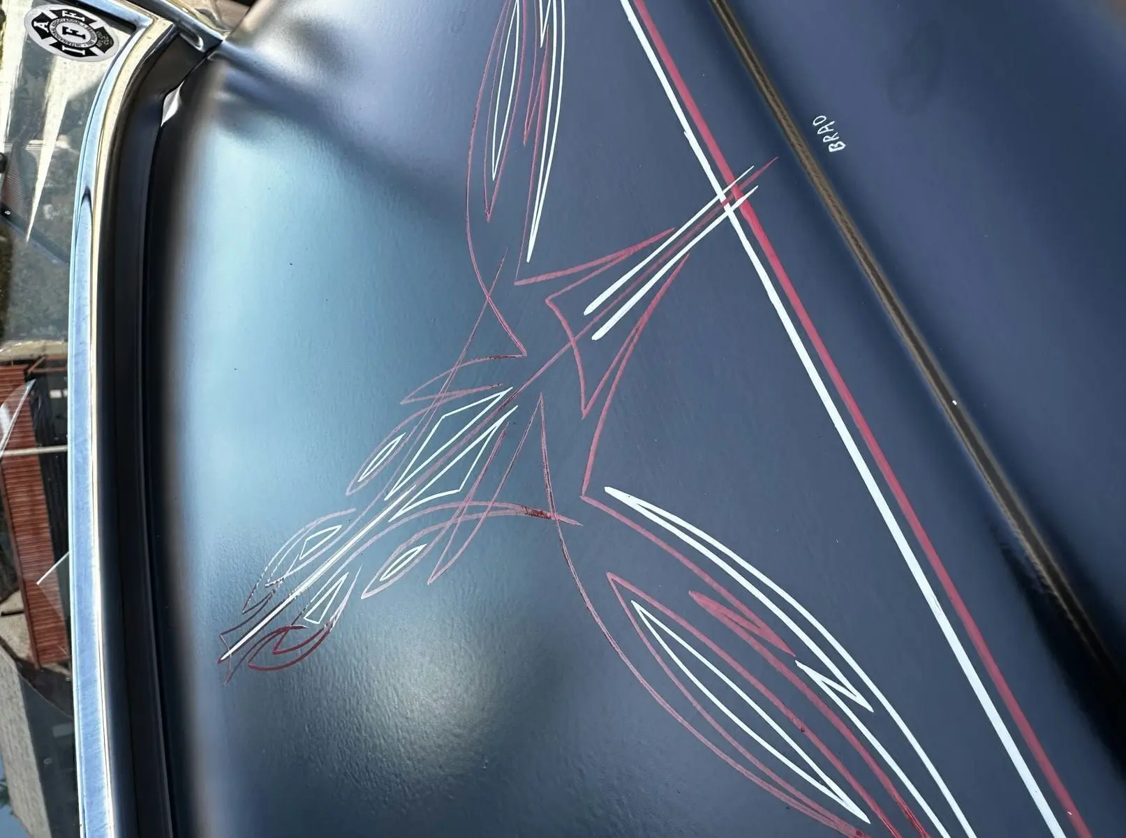 Détail de la peinture noire du capot d'un Ford T Hot Rod 1923, avec liserés rouges et blancs signés "Brad".