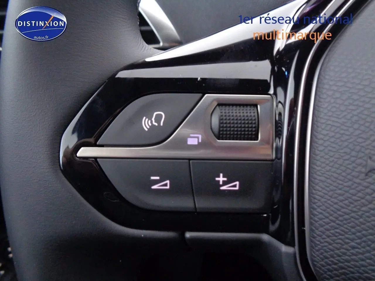 Gros plan sur les commandes de volume et de reconnaissance vocale sur le volant noir brillant d'un Peugeot 3008 2023.