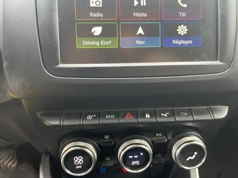 Détail de la console centrale du Dacia Duster blanc Glacier 2019 avec écran tactile et commandes climatisation et aides à la conduite.