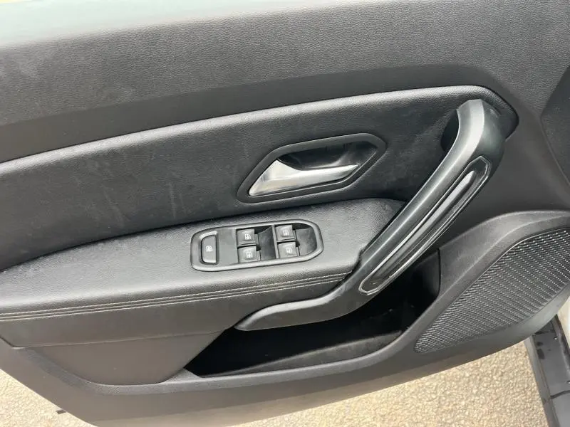 Gros plan sur la porte avant gauche noire du Dacia Duster 2019 avec commandes des vitres électriques et poignée chromée.