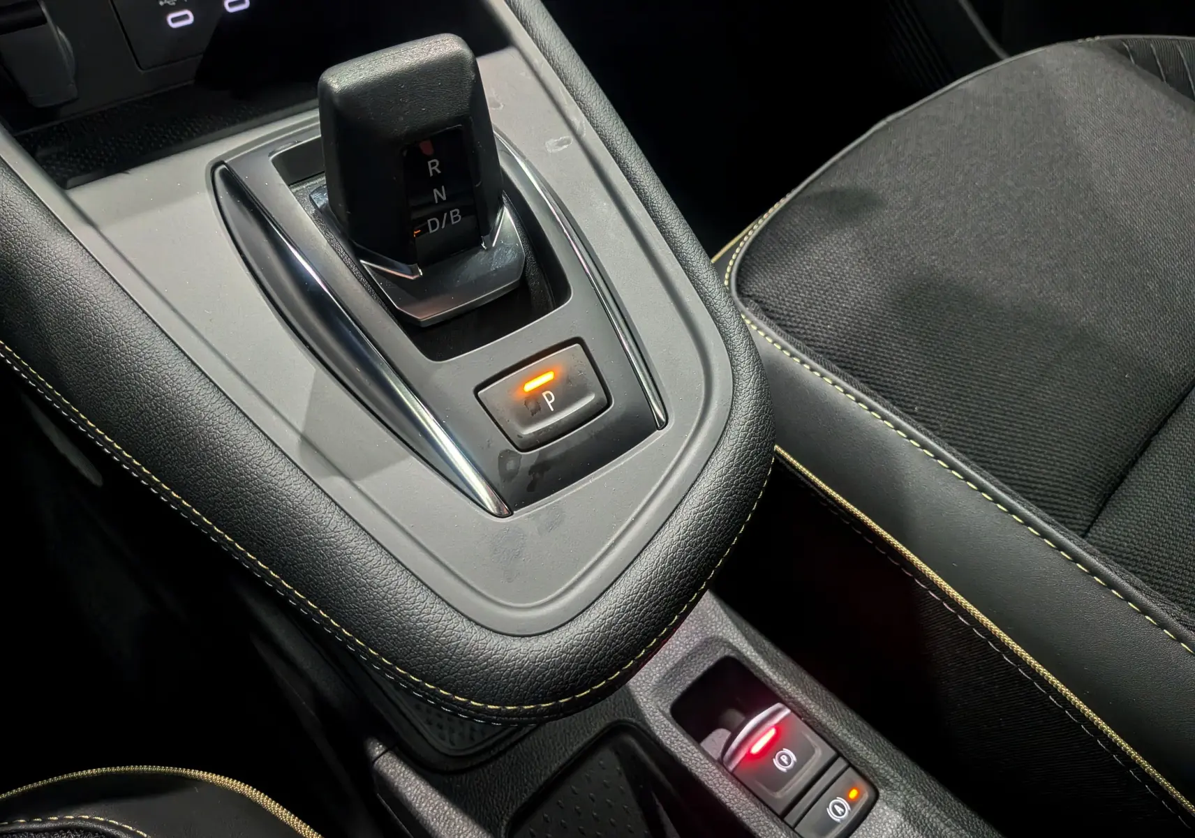 Gros plan sur la console centrale de la Renault SYMBIOZ gris Cassiopé, avec levier de vitesses automatique et siège noir.