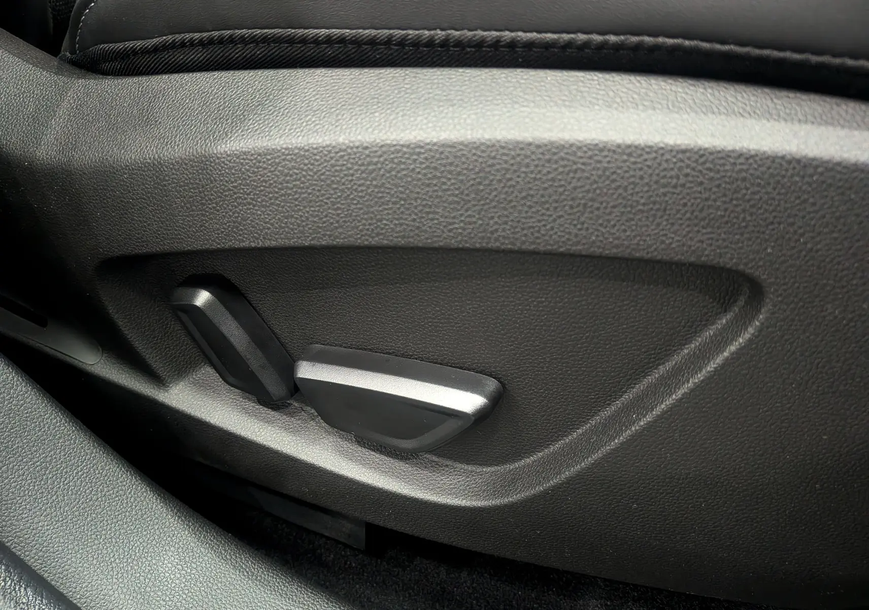 Gros plan sur les commandes de réglage électrique du siège avant en cuir noir du Renault Symbioz hybride 2025.