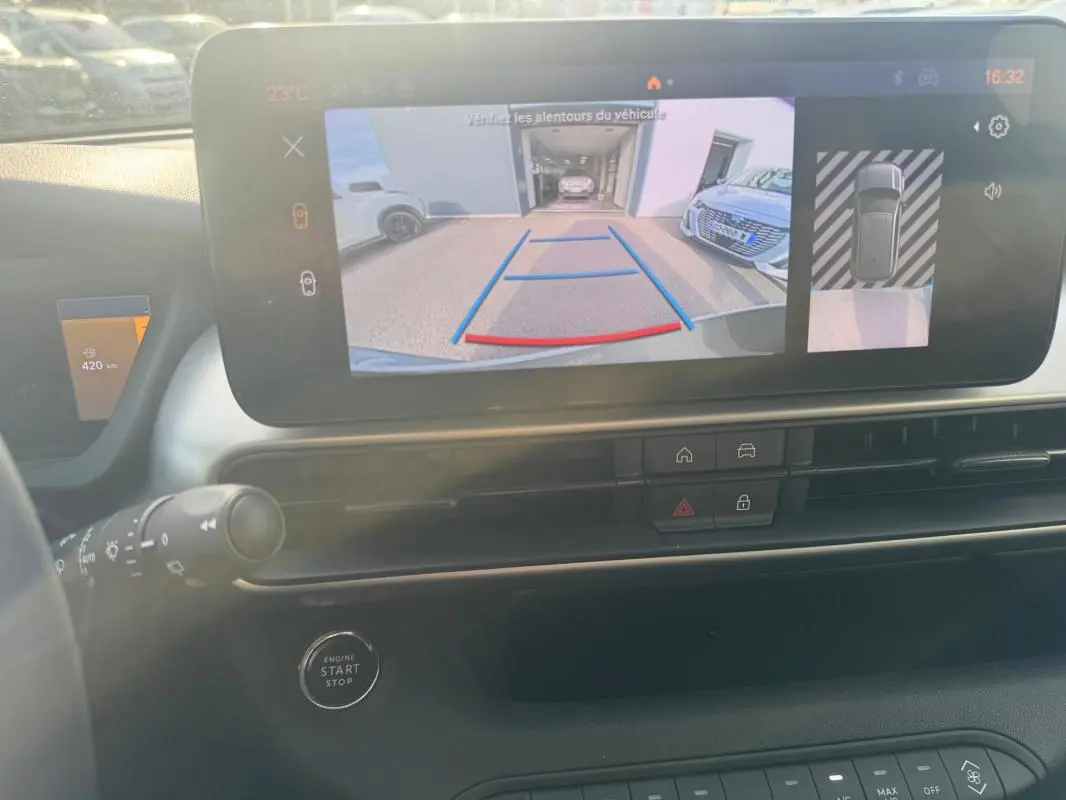 Vue intérieure du tableau de bord du Jeep Avenger gris, écran tactile affichant la caméra de recul et les commandes centrales.