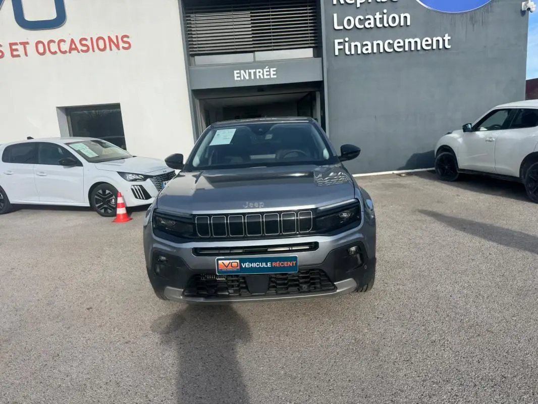 Vue de face d'un Jeep Avenger gris 2025 garé devant un bâtiment avec plaque "Véhicule récent" visible.