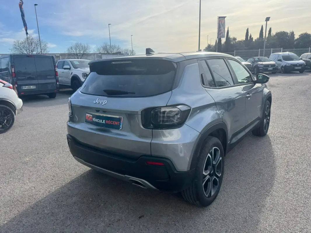 Vue 3/4 arrière droite d'un Jeep Avenger gris avec jantes alliage 18 pouces et vitres teintées, stationné en extérieur.