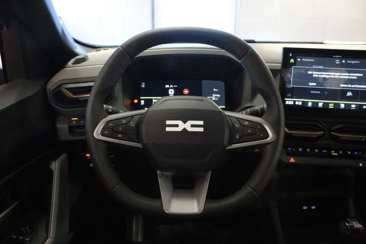 Vue centrée sur le volant cuir noir du Dacia Bigster 2026 avec tableau de bord digital et écran tactile.