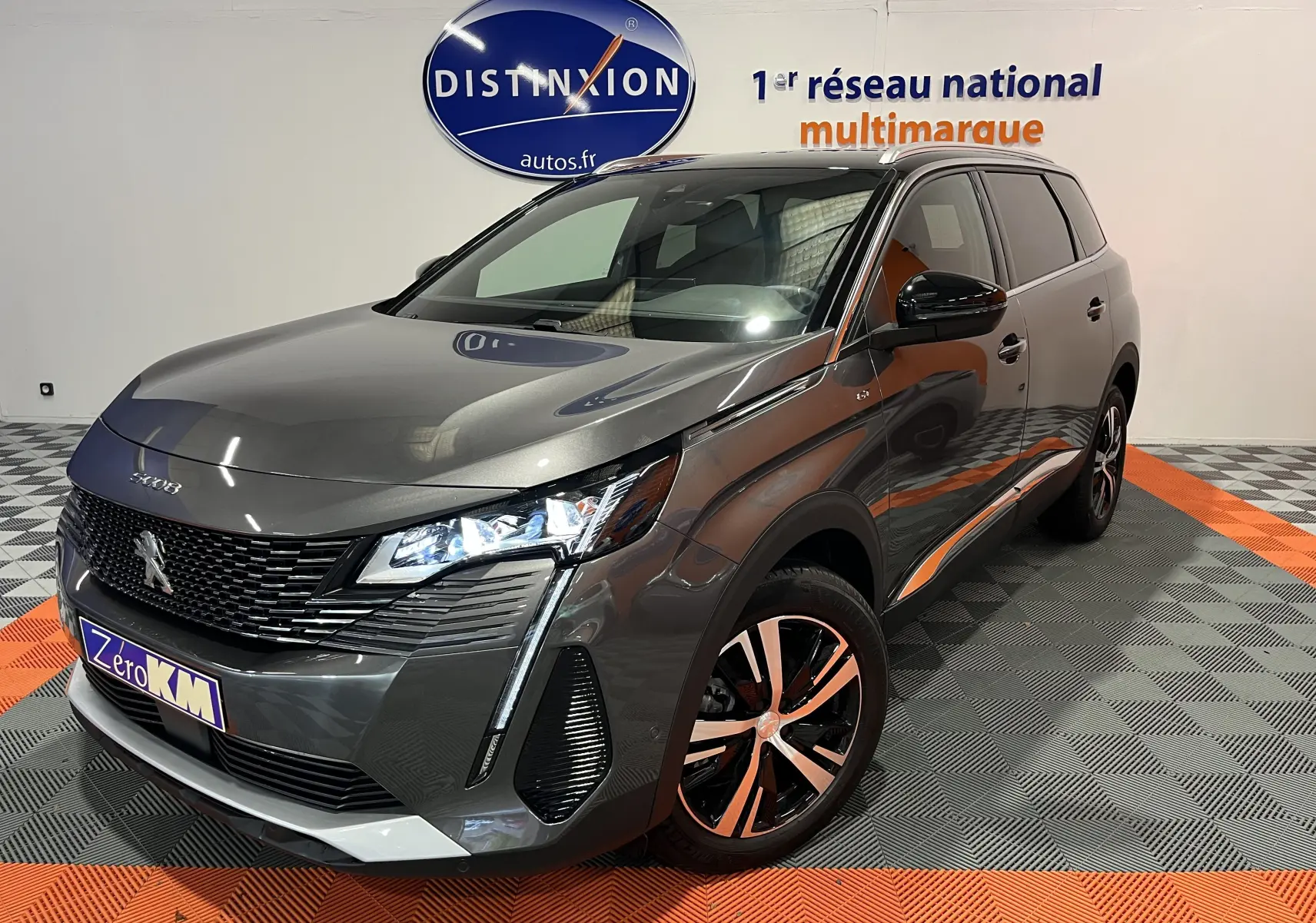 Vue 3/4 avant droit d'un Peugeot 5008 gris platinium 2024 avec phares LED et jantes alliage bicolores.