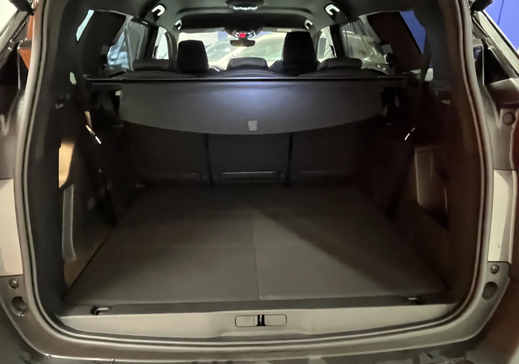 Vue rapprochée du volant noir du Peugeot 5008 2024 GT avec commandes intégrées et logo lion central argenté.