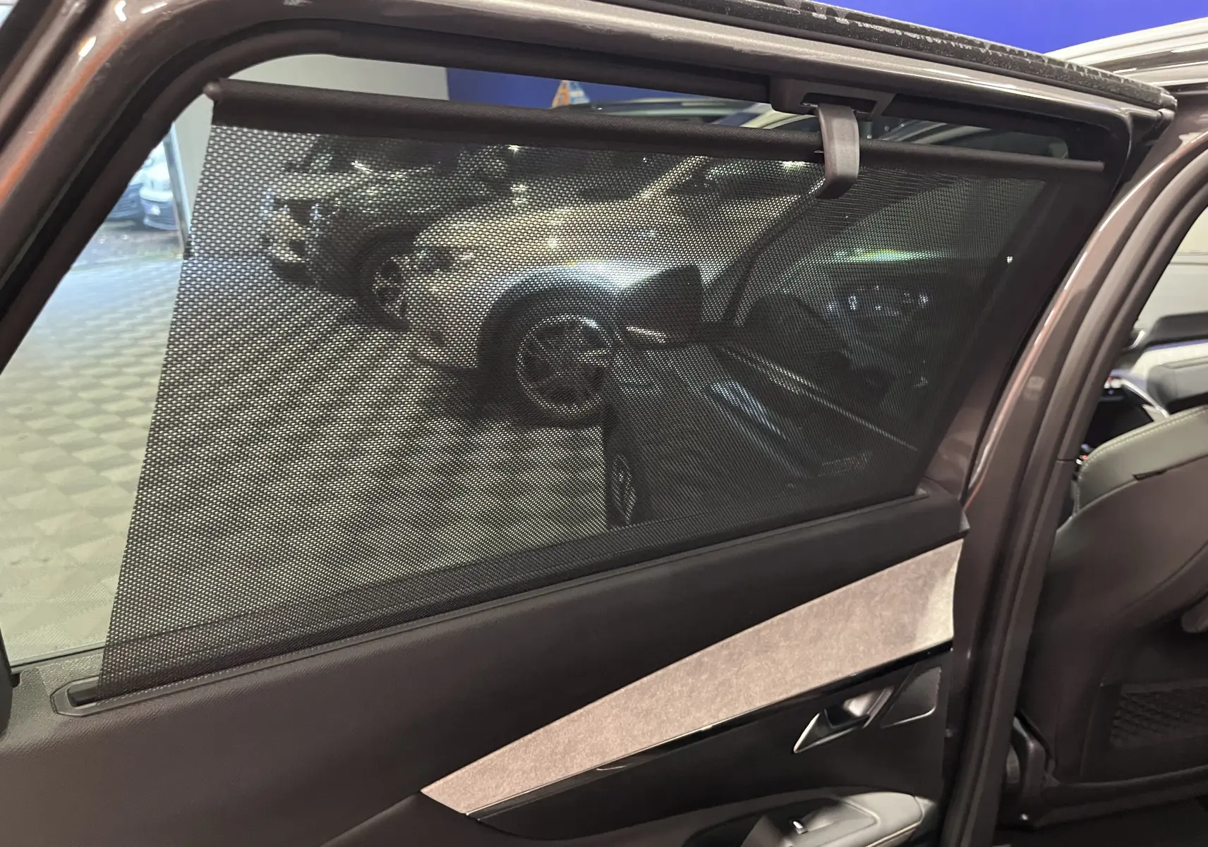 Détail de la console arrière noire du Peugeot 5008 2024 avec ventilation, prise 12V et ports USB doubles.