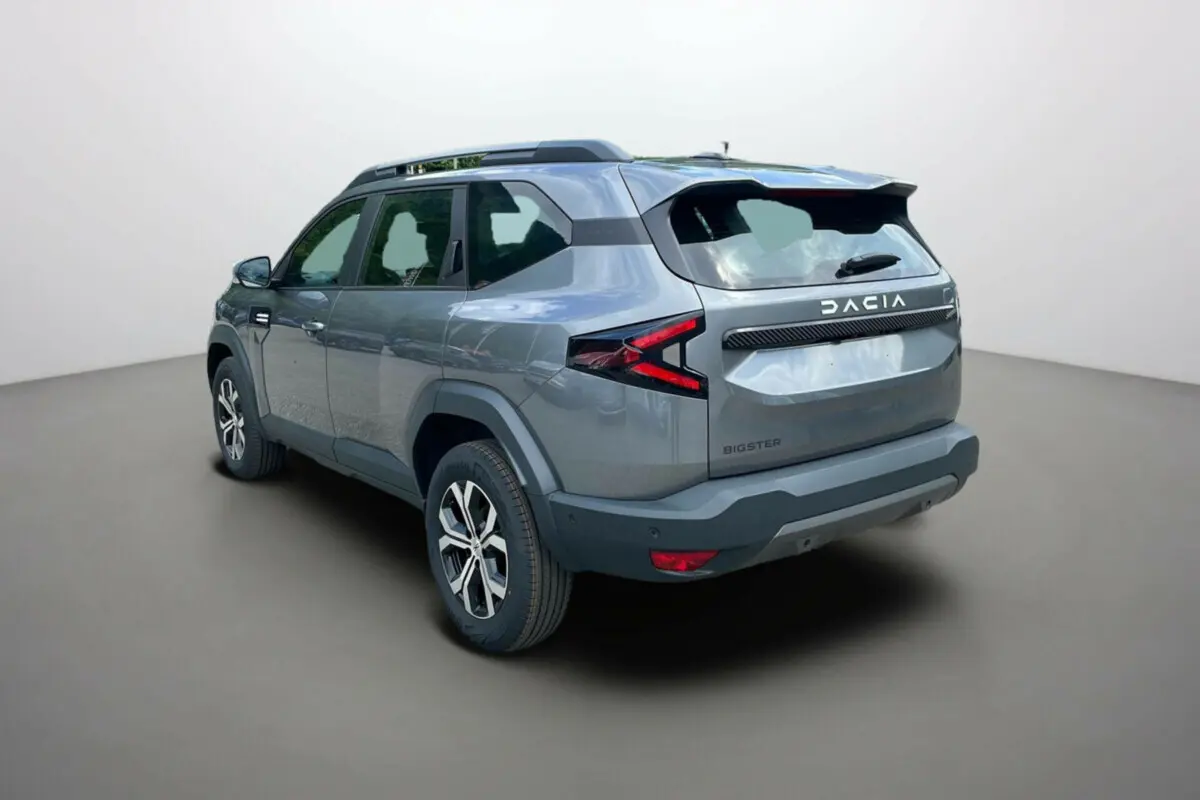 Vue 3/4 arrière droit du SUV Dacia Bigster gris schiste avec barres de toit et jantes alu 17 pouces.