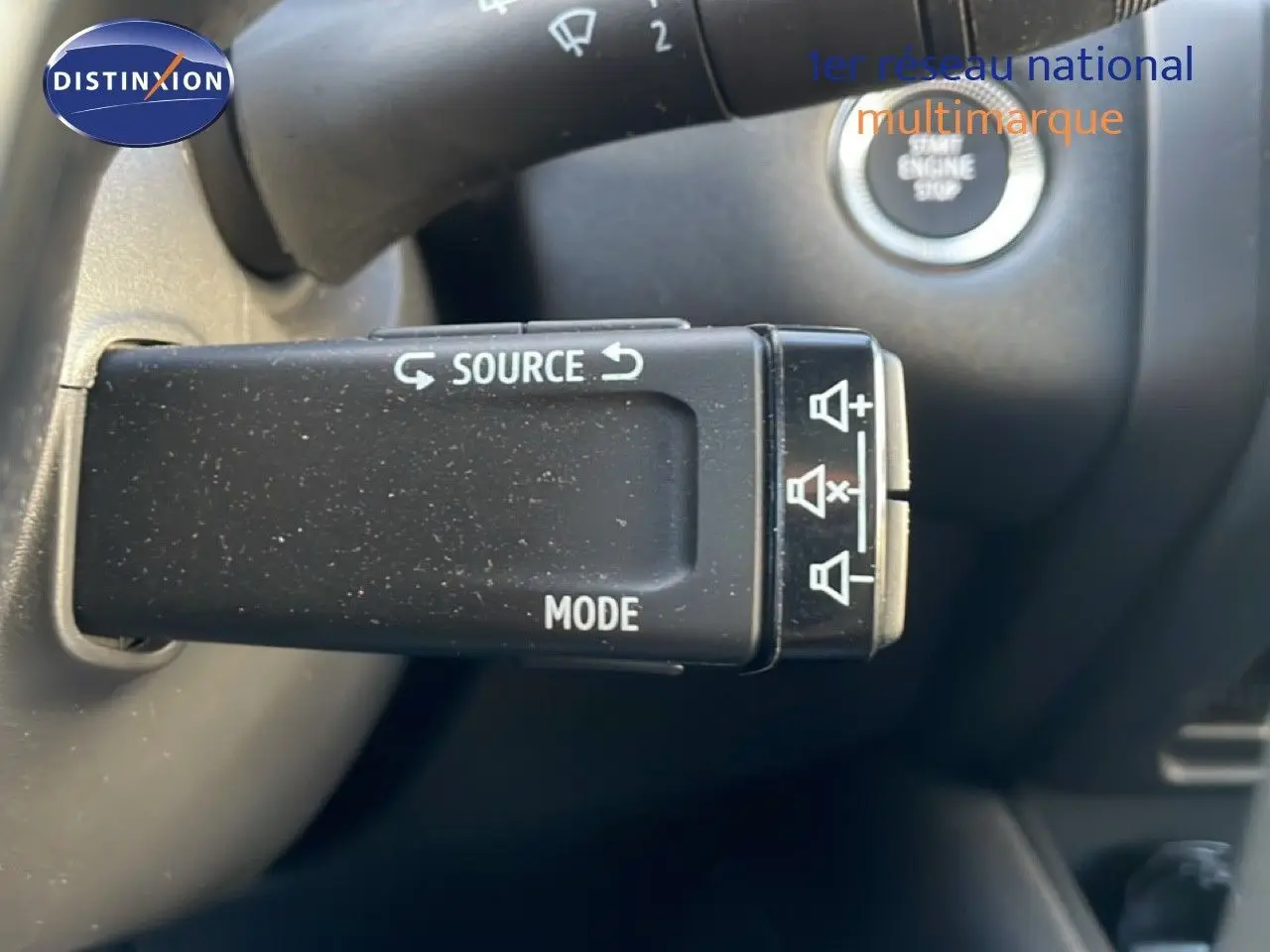 Gros plan sur la commande au volant du Renault Symbioz gris cassiopée, avec bouton source et mode visible.