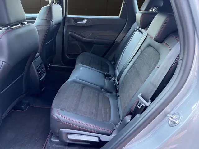 Vue intérieure côté droit des sièges arrière du Ford Kuga gris 2024, avec sellerie mixte cuir et tissu et surpiqûres rouges.