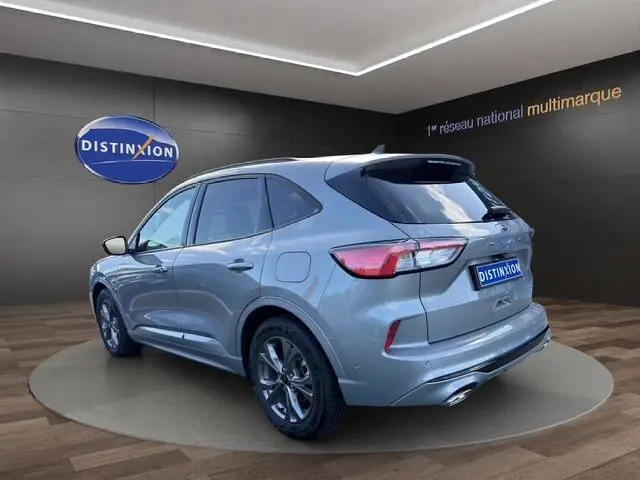 Vue 3/4 arrière d'un Ford Kuga gris 2024 ST-Line X, soulignant ses lignes dynamiques et ses jantes alliage foncé.