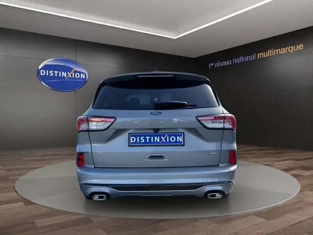 Vue arrière d'un Ford Kuga gris 2024, version hybride ST-Line X, avec double sortie d'échappement et logo Distinxion.
