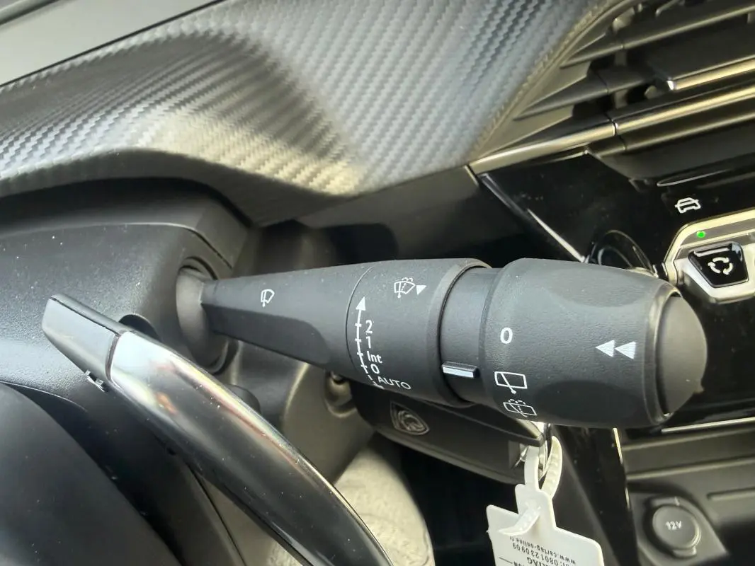 Gros plan sur la commande des essuie-glaces du Peugeot 208 Hybrid 110 gris, côté gauche du volant.