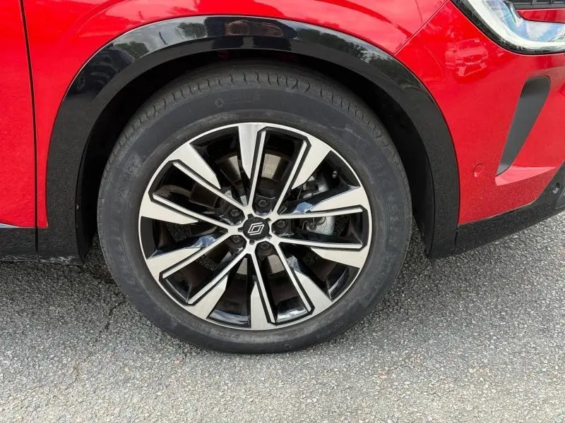 Gros plan sur la roue avant gauche du Renault Austral Rouge Flamme 2025, avec jante alliage bicolore et passage de roue noir.