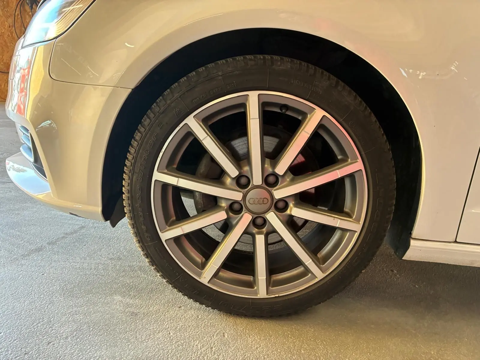 Gros plan sur la roue avant gauche d'une Audi A3 Sportback blanche de 2019 avec jante alliage à dix branches.