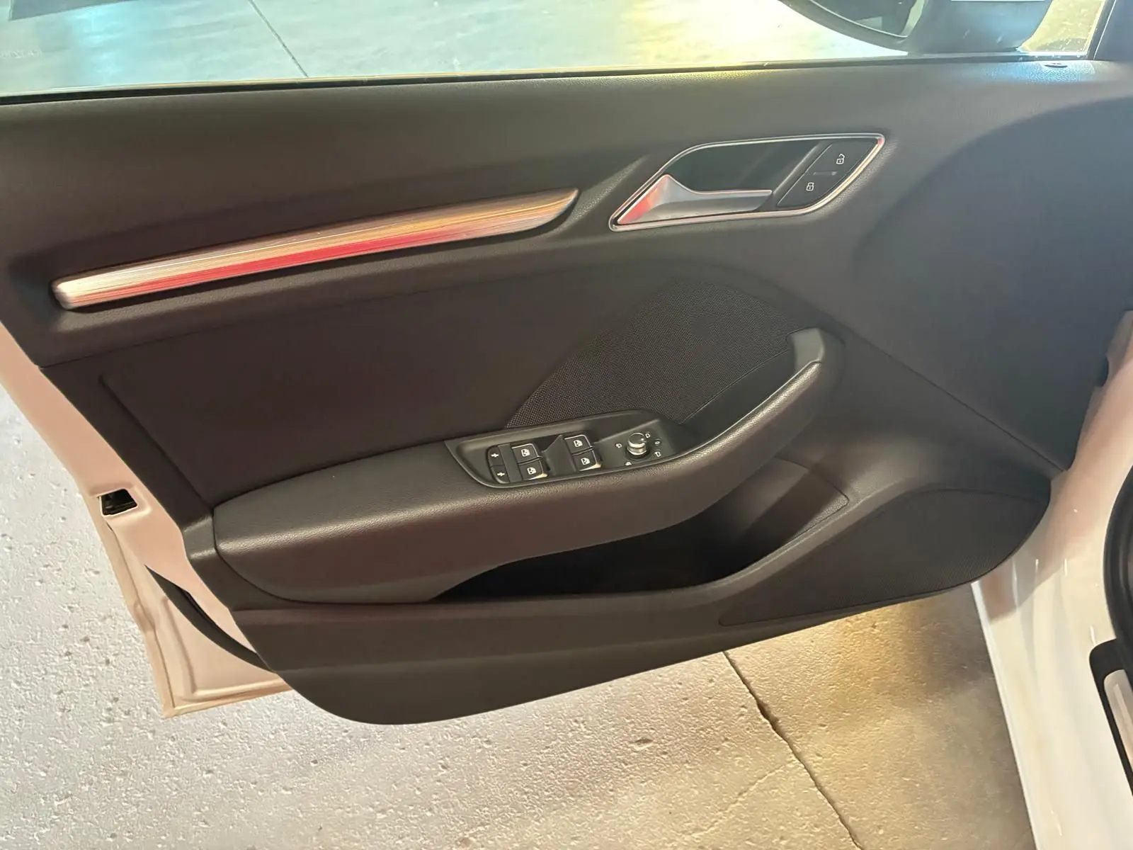 Vue intérieure de la porte avant gauche noire de l'Audi A3 Sportback blanche avec commandes de vitres et verrouillage.