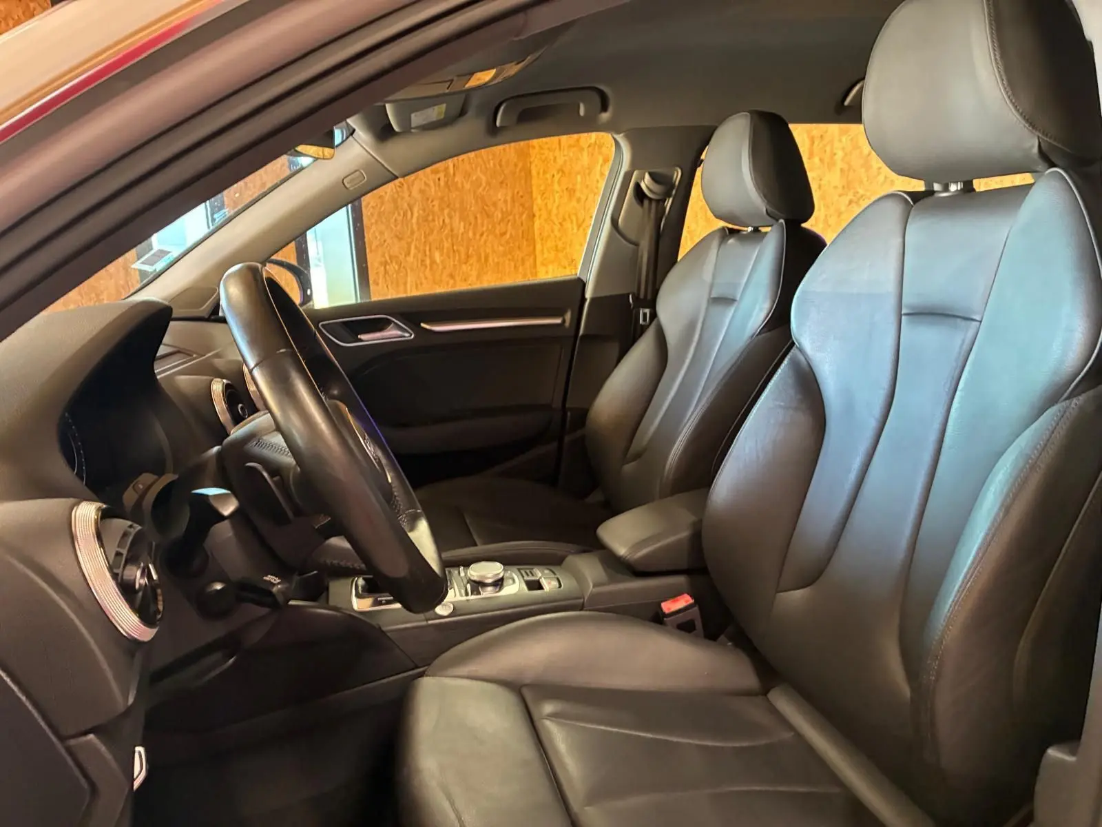 Vue intérieure côté conducteur de l'Audi A3 Sportback 2019 avec sièges cuir noir et tableau de bord moderne.