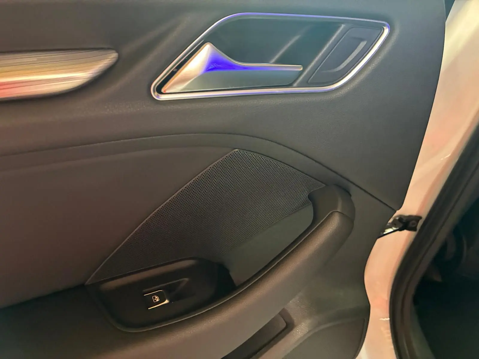Détail de la porte intérieure côté gauche en cuir noir de l'Audi A3 Sportback blanc, avec poignée et bouton de verrouillage.
