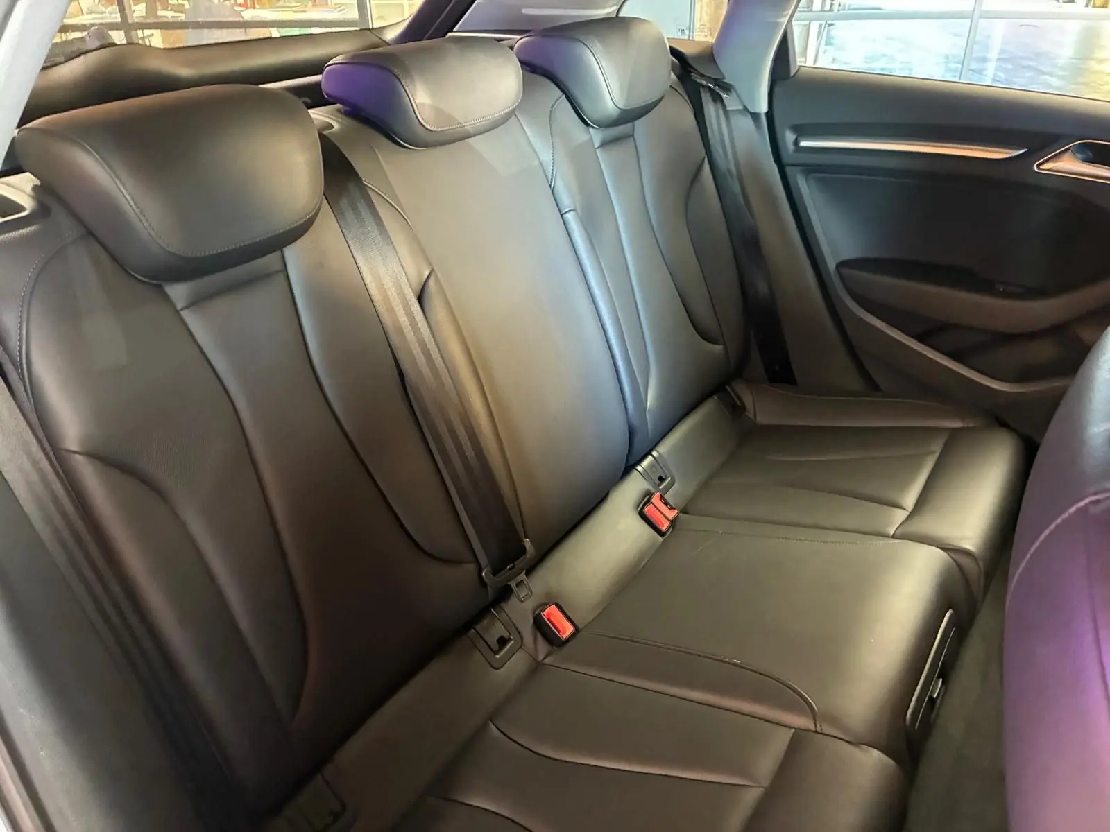 Vue intérieure sur la banquette arrière en cuir noir de l'Audi A3 Sportback, avec ceintures de sécurité visibles.