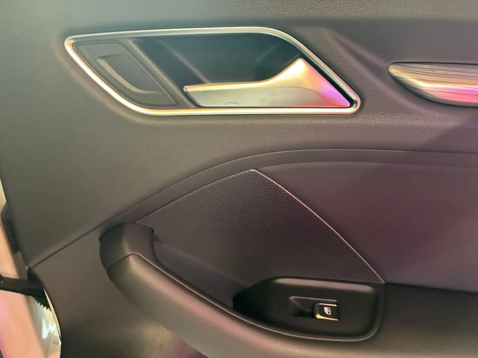 Détail de la poignée intérieure côté gauche en plastique noir avec insert chromé sur une Audi A3 Sportback blanche.