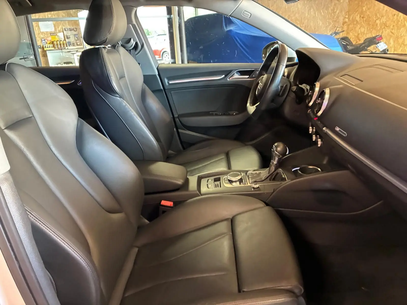 Vue intérieure côté conducteur de l’Audi A3 Sportback 2019 avec sièges cuir noir et tableau de bord moderne.