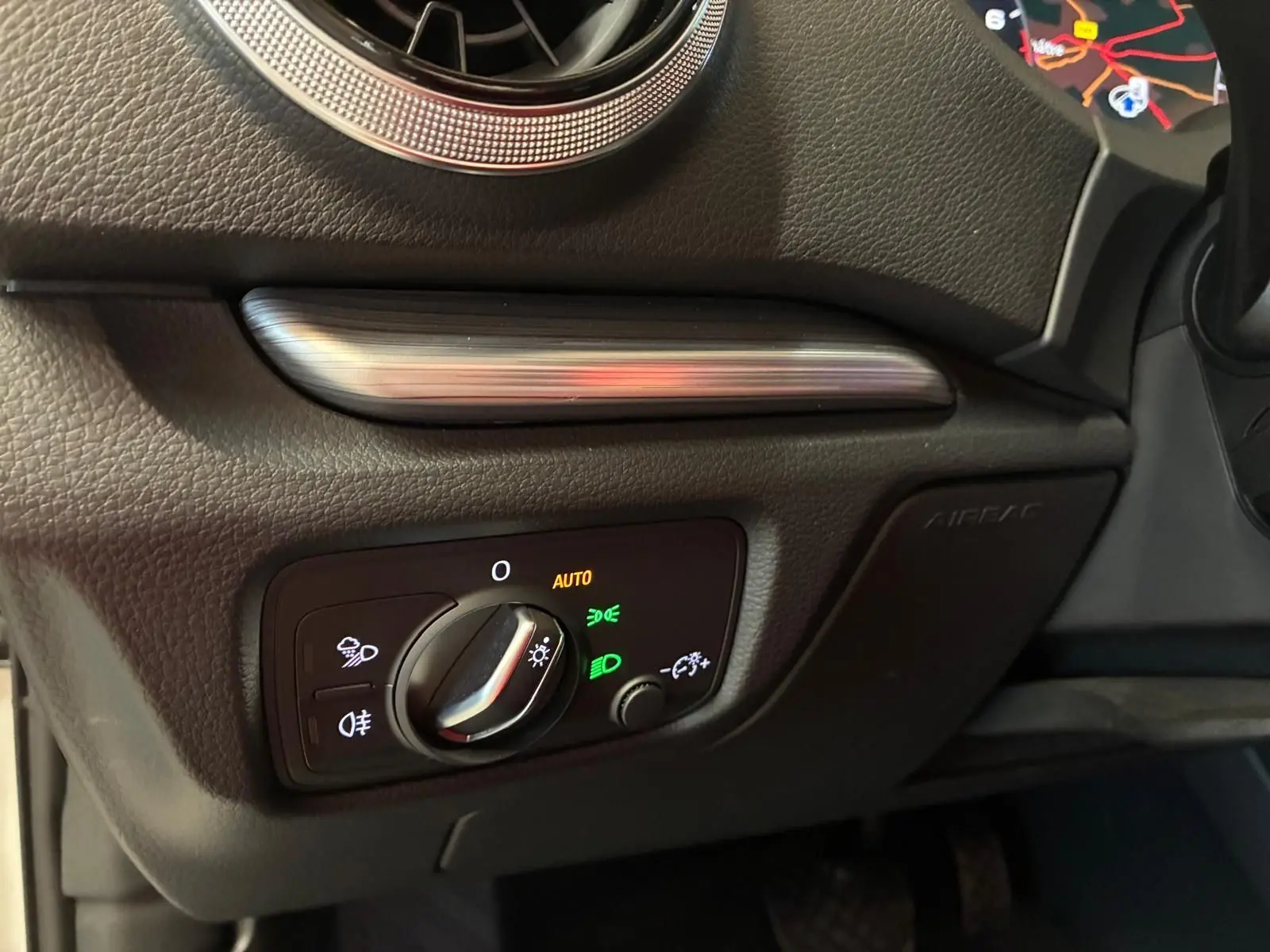 Détail du tableau de bord côté gauche d'une Audi A3 Sportback blanche, avec commande des phares en mode auto et éclairage LED.