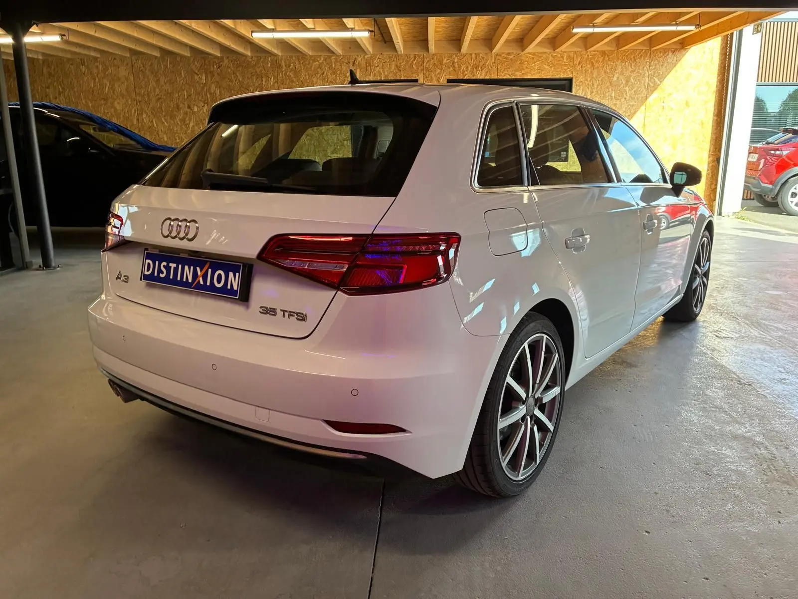 Audi A3 Sportback blanc vue 3/4 arrière droit, avec jantes alliage et feux arrière LED distinctifs.
