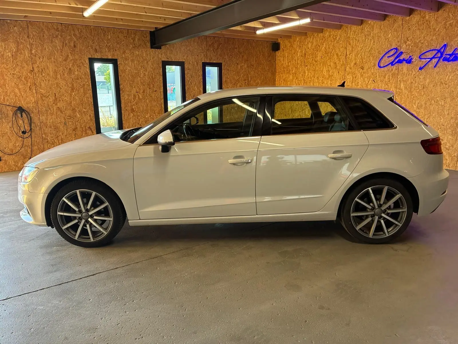 Audi A3 Sportback blanc vue de profil côté gauche, avec jantes alliage et intérieur noir visible à travers les vitres.