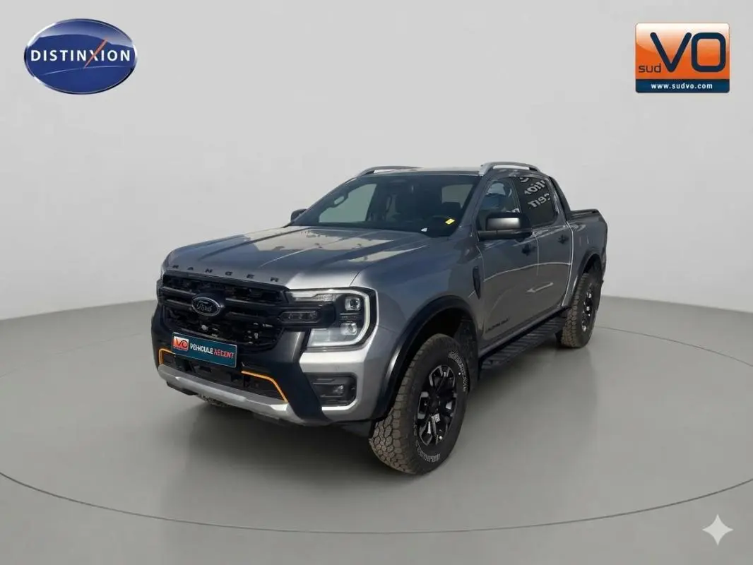 Vue 3/4 avant droite du Ford Ranger gris 2025 avec barres de toit et jantes alliage noires.