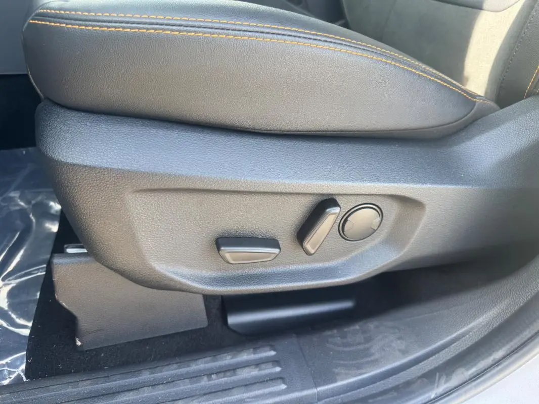Gros plan sur les commandes de réglage électrique du siège passager en cuir gris avec surpiqûres orange du Ford Ranger 2025.